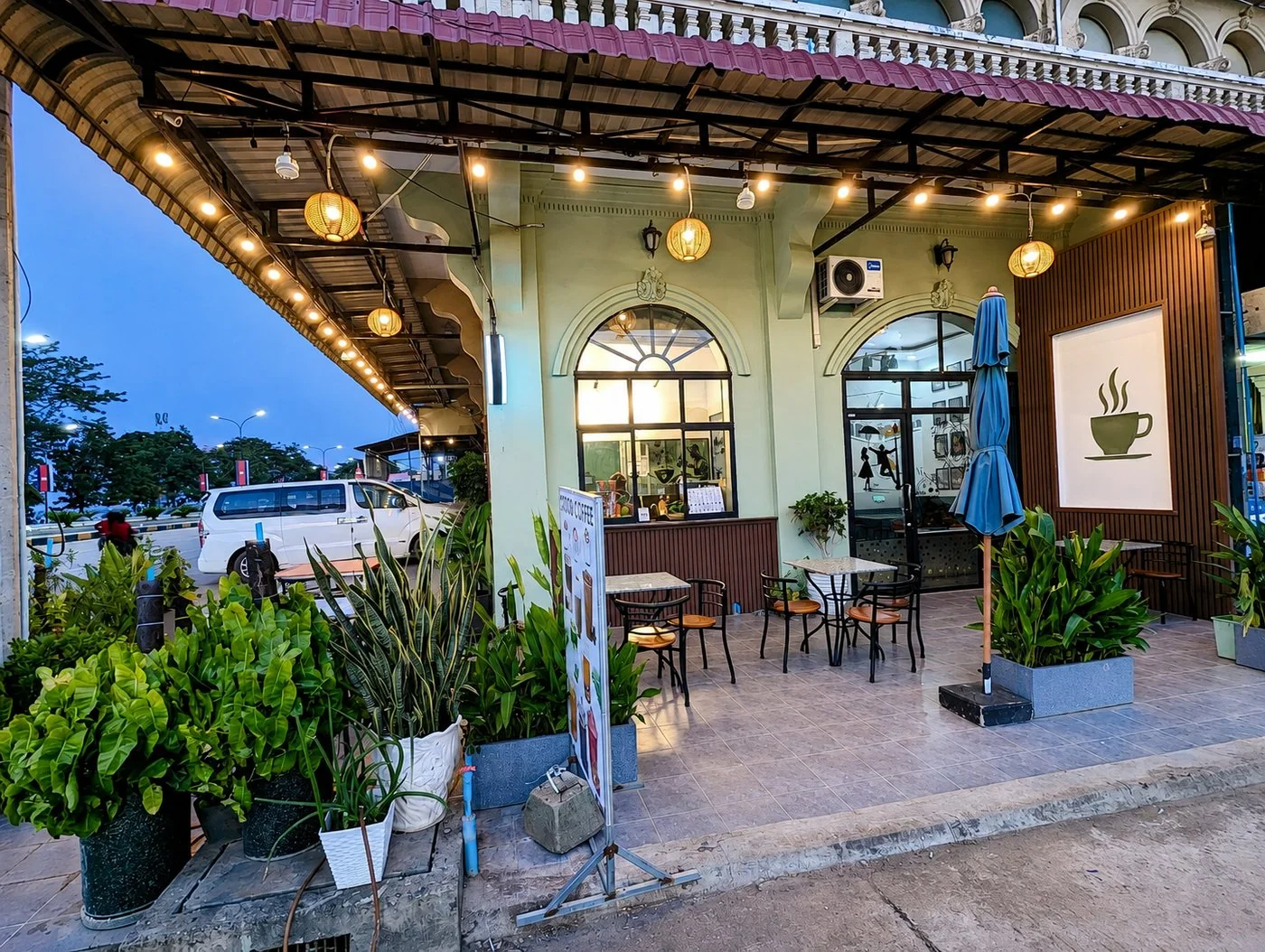 Sampheap Guesthouse café storefront with outdoor seating lit up in the evening